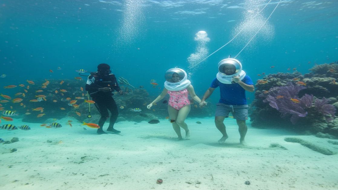 Guide assisting a tourist during sea walk at North Bay Island, Andaman